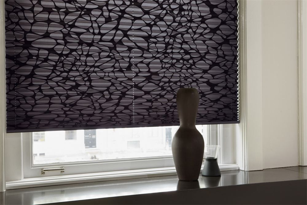 Window with a dark patterned blind, white sill, and a wooden vase silhouette on the ledge.