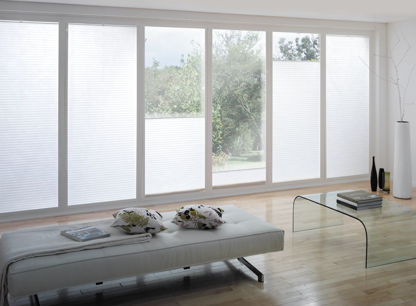Bright minimalist living room with large windows, a sofa, coffee table, and white blinds.