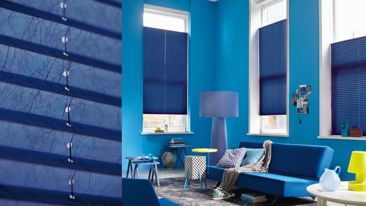Blue living room with striped blue blinds, sofa, lamp, and patterned cushions in modern decor