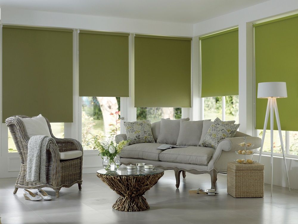Modern living room with green window shades, gray sofa, wicker chair, and floor lamp