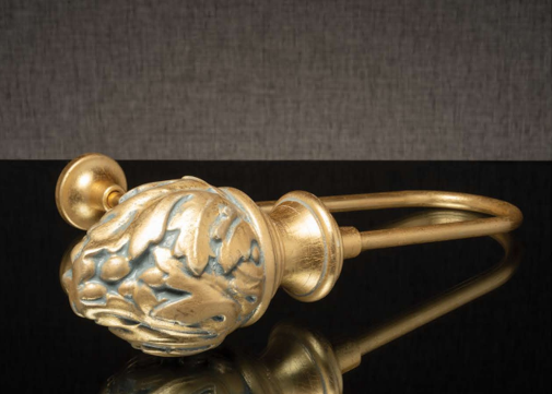 Gold bracelet with a decorative sculpted clasp on a dark background