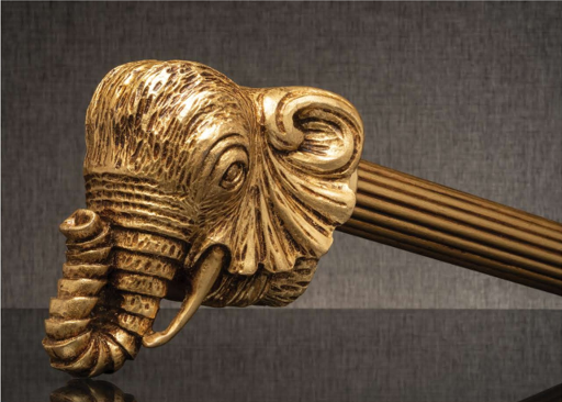 Golden elephant-head sculpture with tusks on a dark textured background