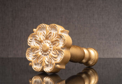 Gold floral decorative knob on a dark reflective surface