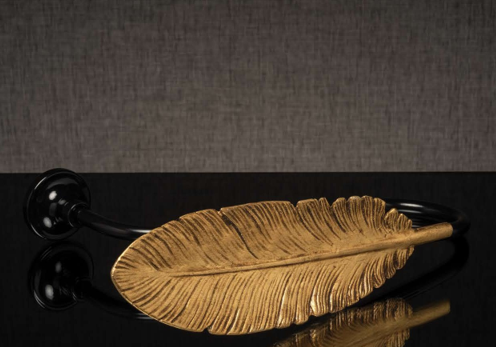 Gold feather-shaped object on a black background with a small black cord attached