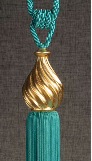 Teal tassel with braided cord and gold decorative finial on a dark background