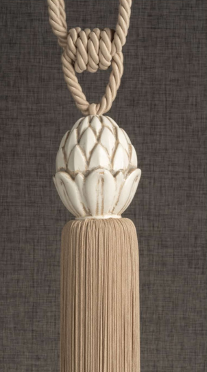 Beige braided tassel with a carved white wooden finial against a dark textured background