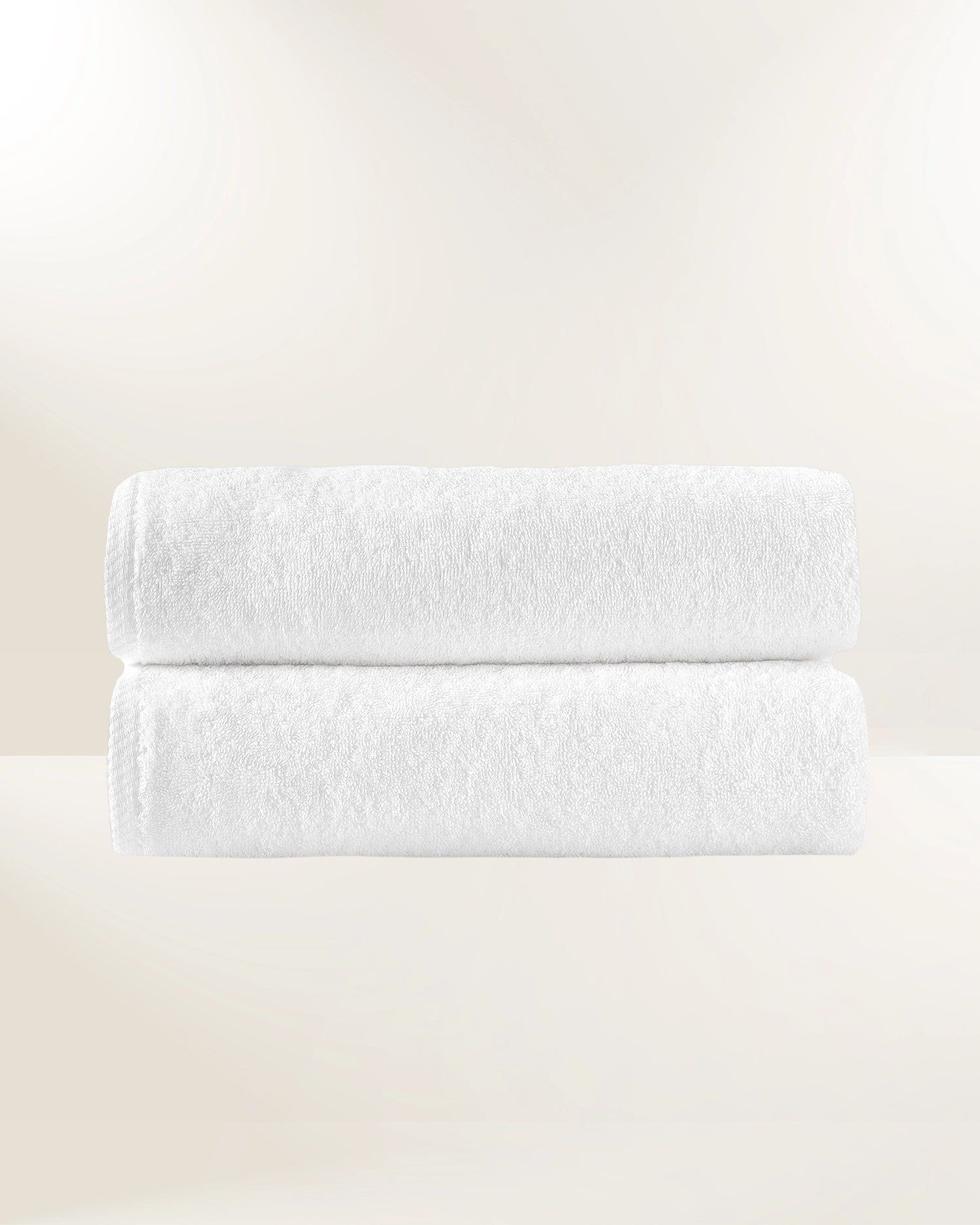 Two stacked white textured towels on a light beige background