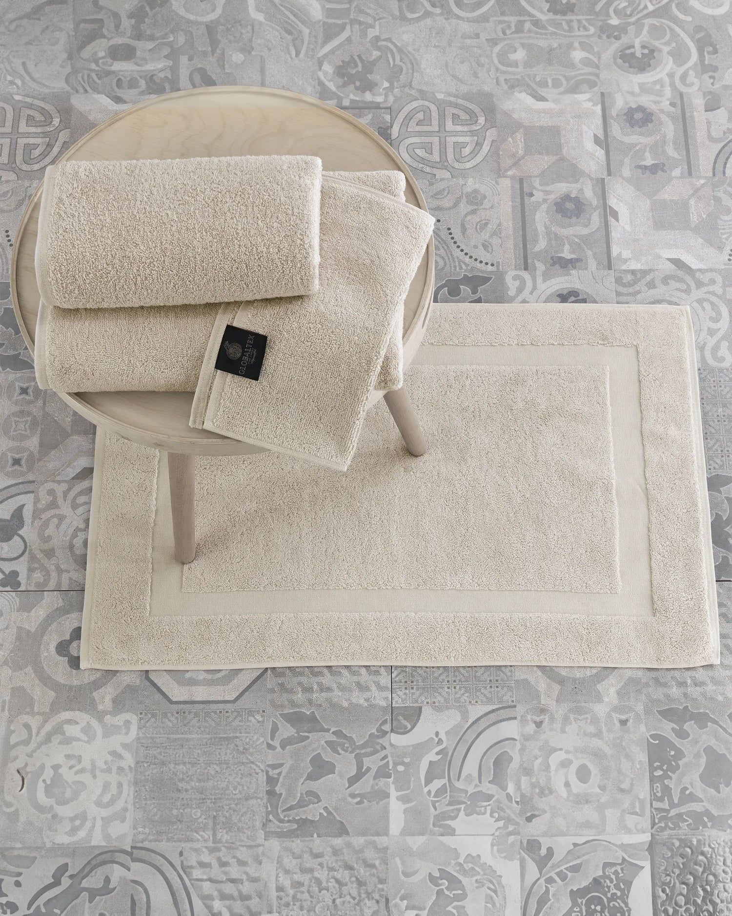 Beige upholstered chair and matching rug on a patterned gray floor