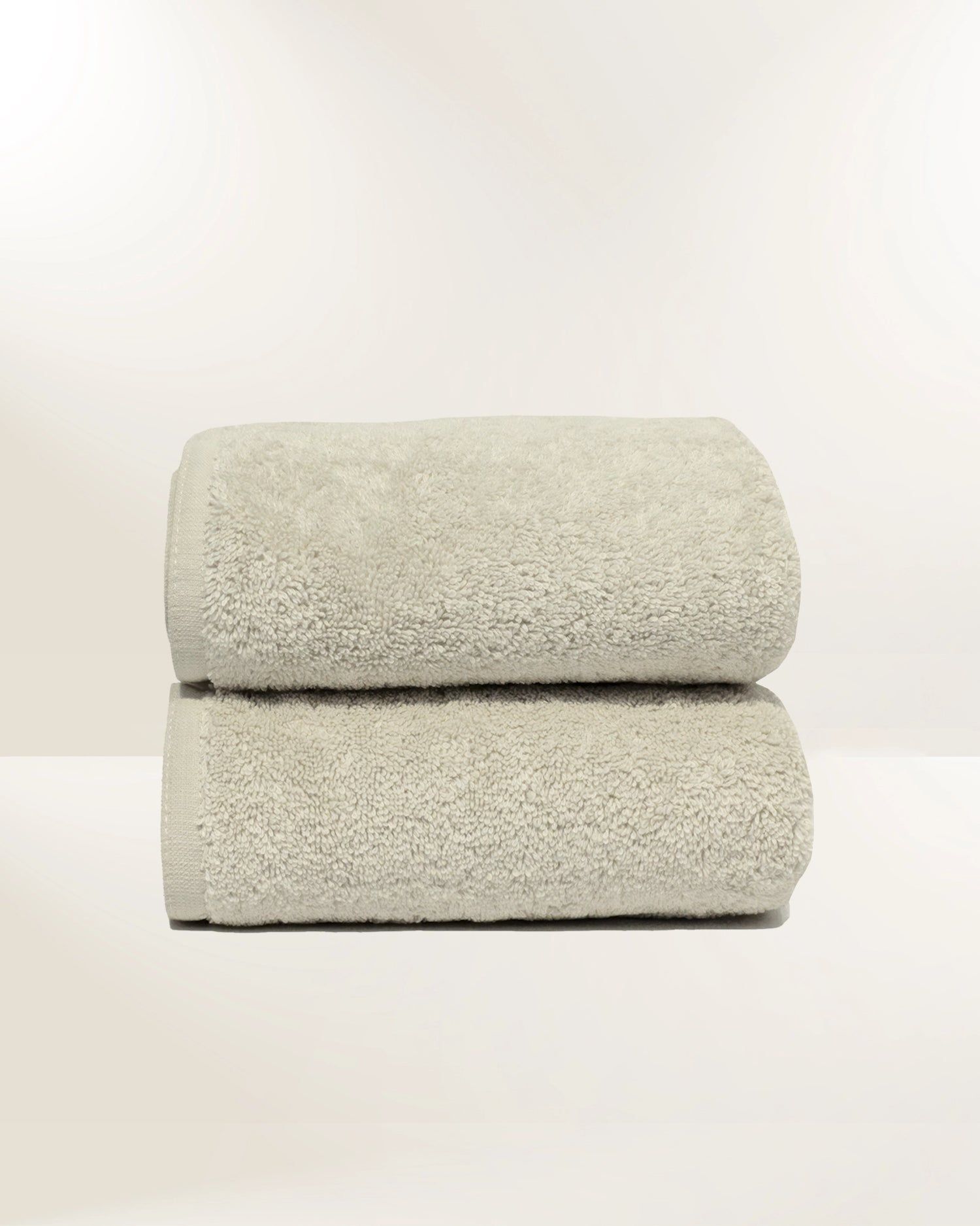 Two folded light gray towels stacked on a white background