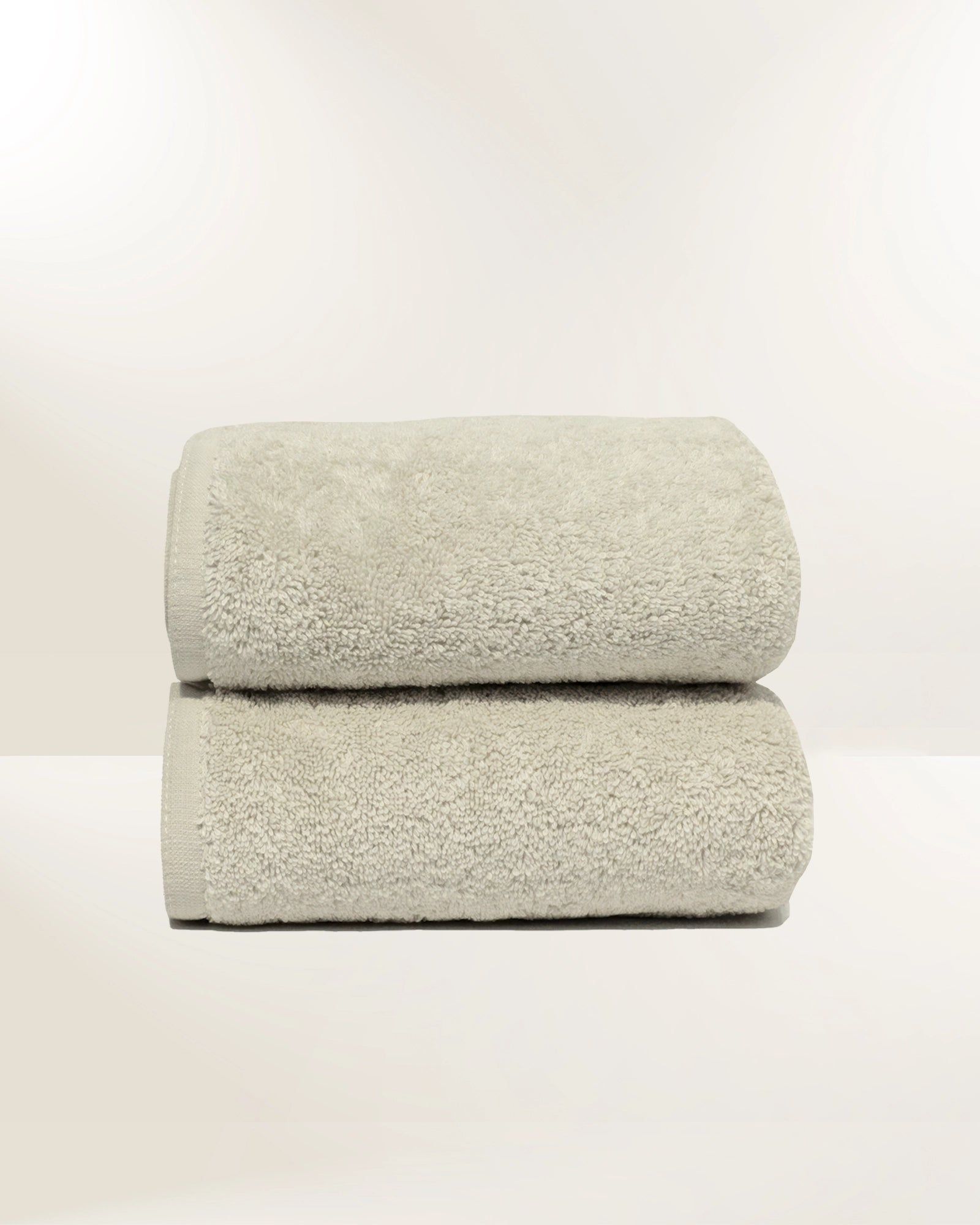 Two folded gray towels stacked on a white surface against a plain background