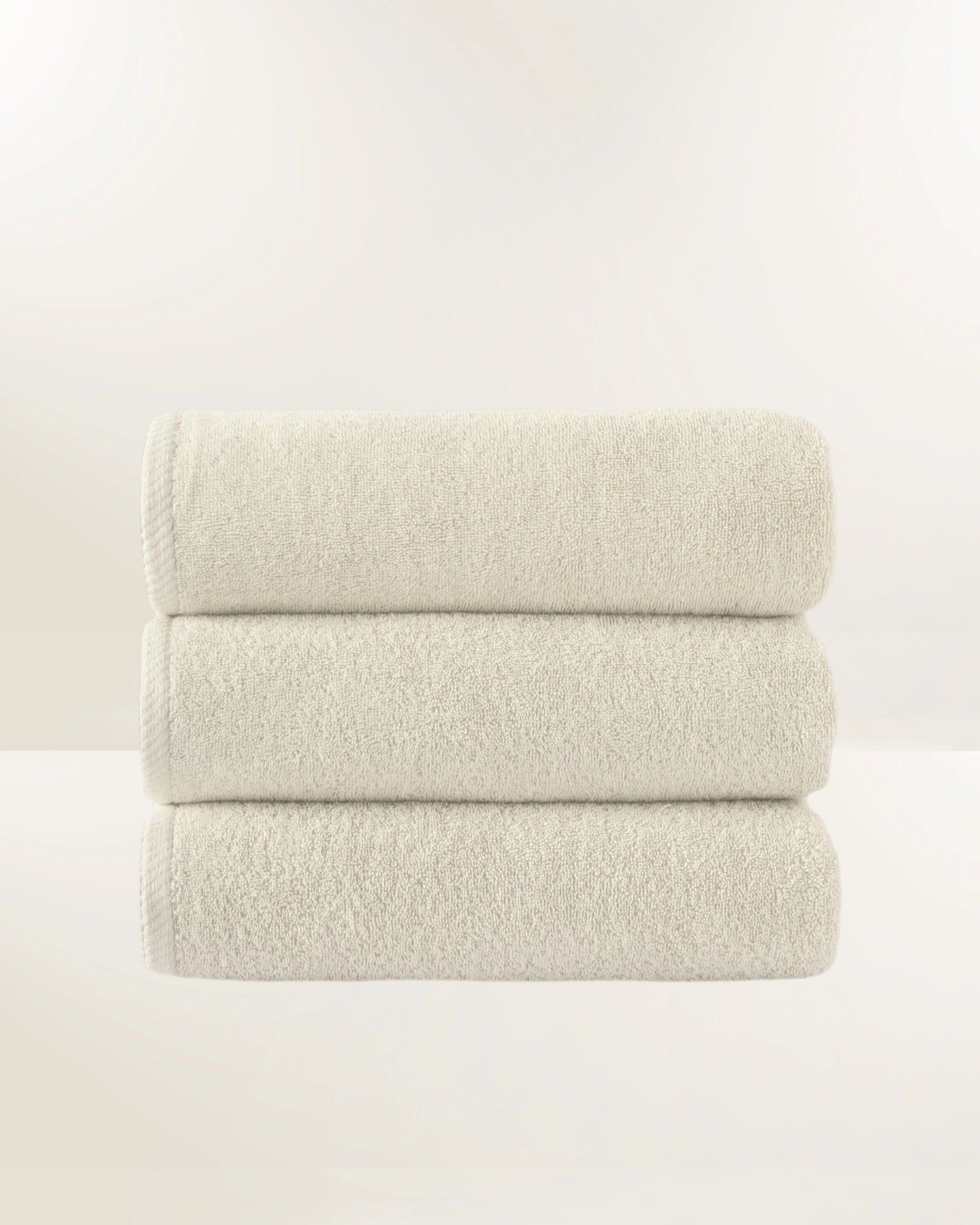Three stacked speckled beige cushions on a plain white background