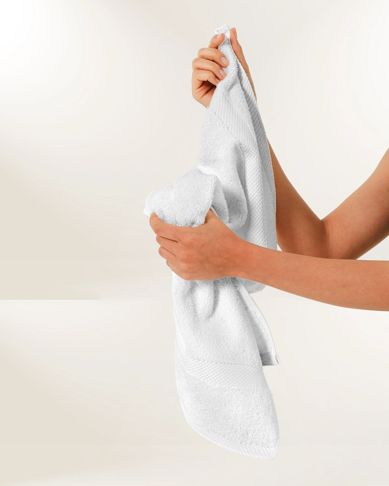 Hands wringing a white towel over a sink.