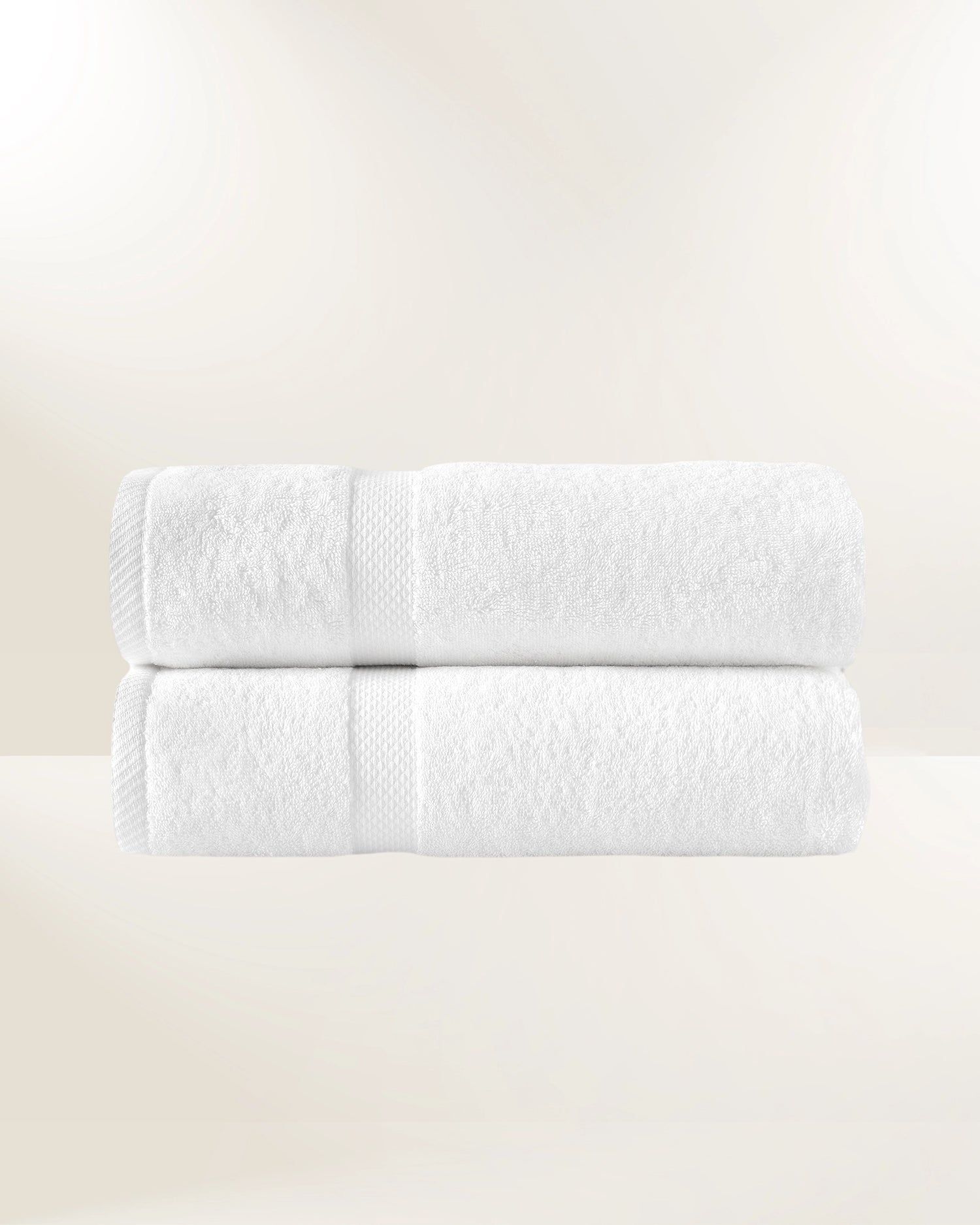 Two folded white towels stacked on a light beige background