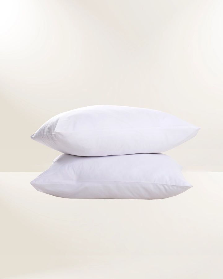 Two white pillows stacked on a light beige background