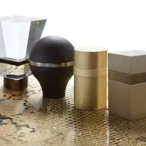 Four decorative perfume bottles on a gold patterned surface, including black, gold, and beige containers.