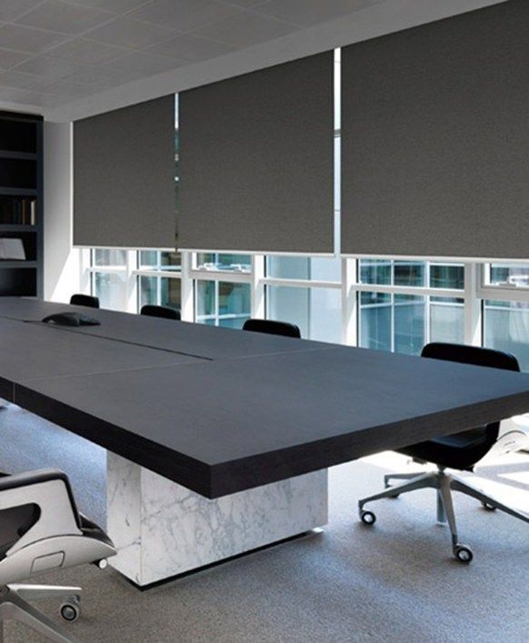Modern conference room with a large table, swivel chairs, and gray window blinds