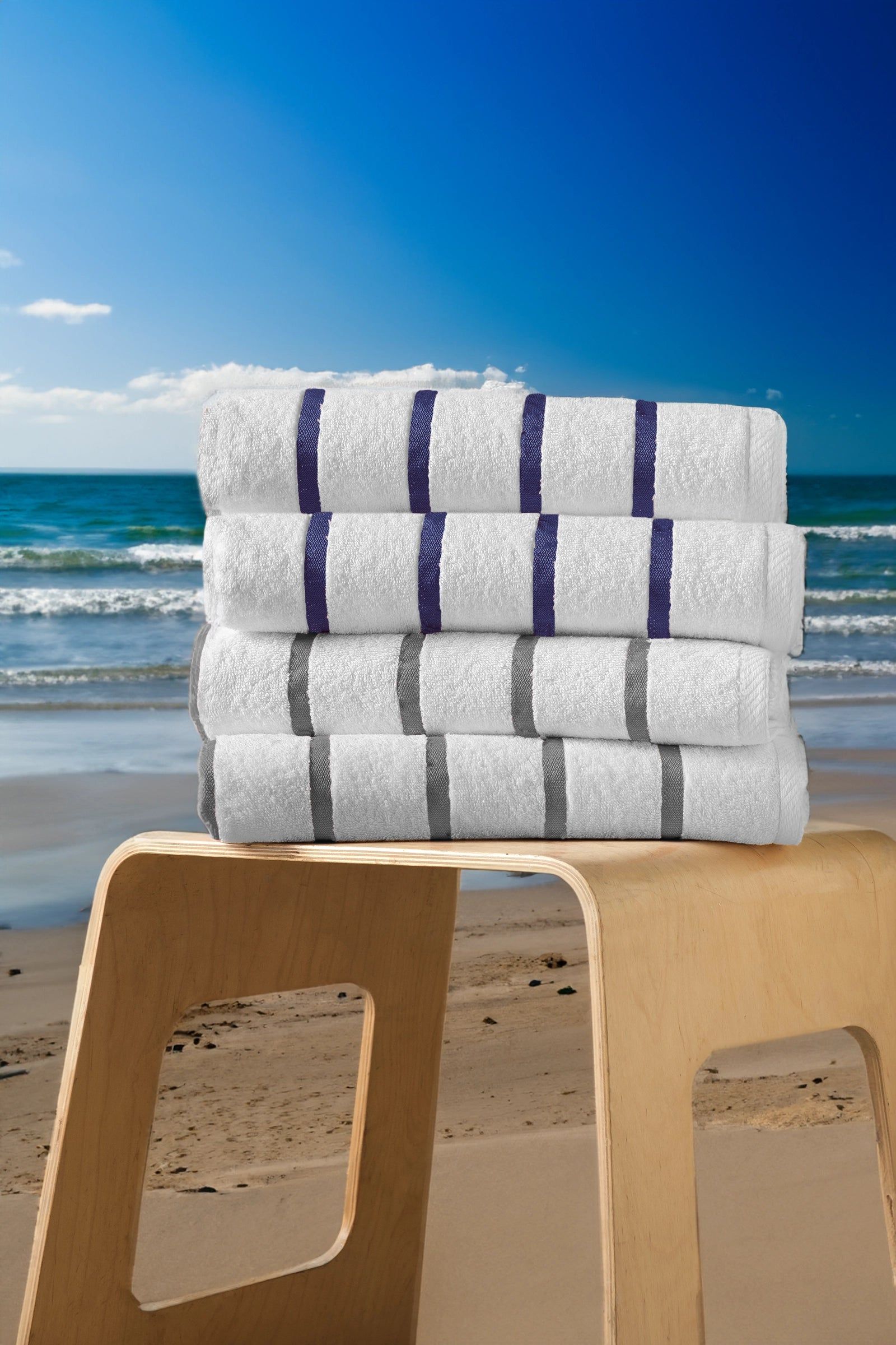 Stacked white towels with purple stripes on a stool at a sunny beach