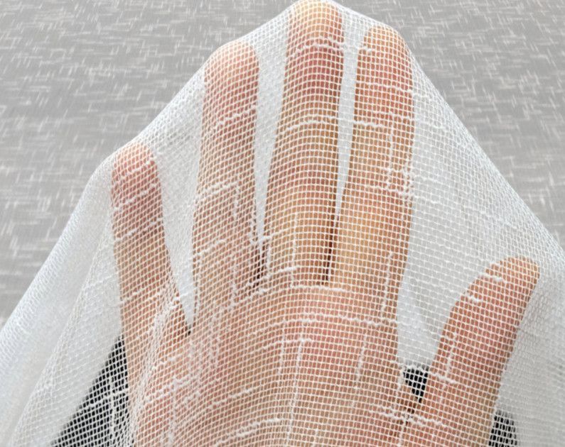 Hand pressing against white mesh fabric, with a gray patterned background.