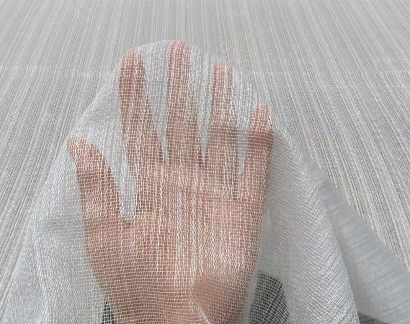 Hand pressing against sheer white fabric curtain, creating a faint silhouette.