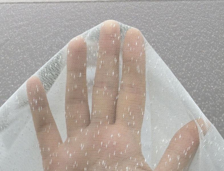 Hand behind a translucent mesh fabric against a gray background