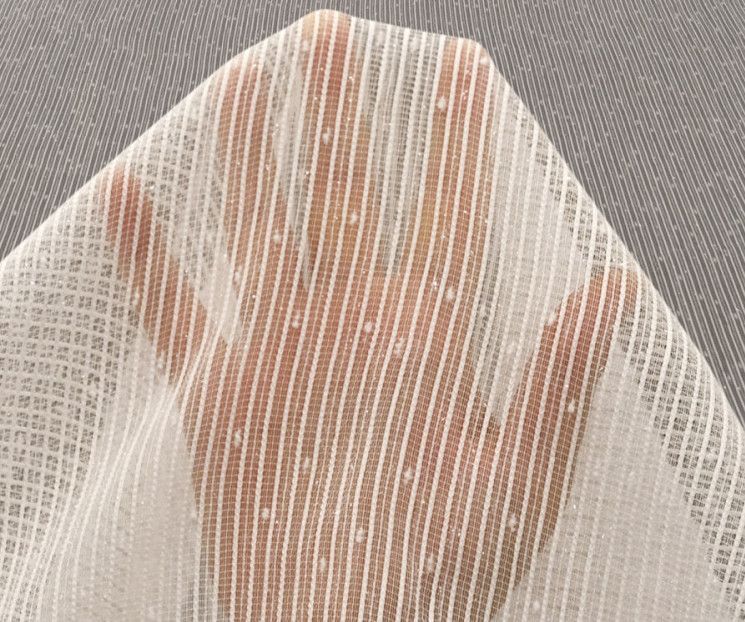 Hand pressing against white sheer fabric, creating a silhouetted handprint and warm orange stripes behind it