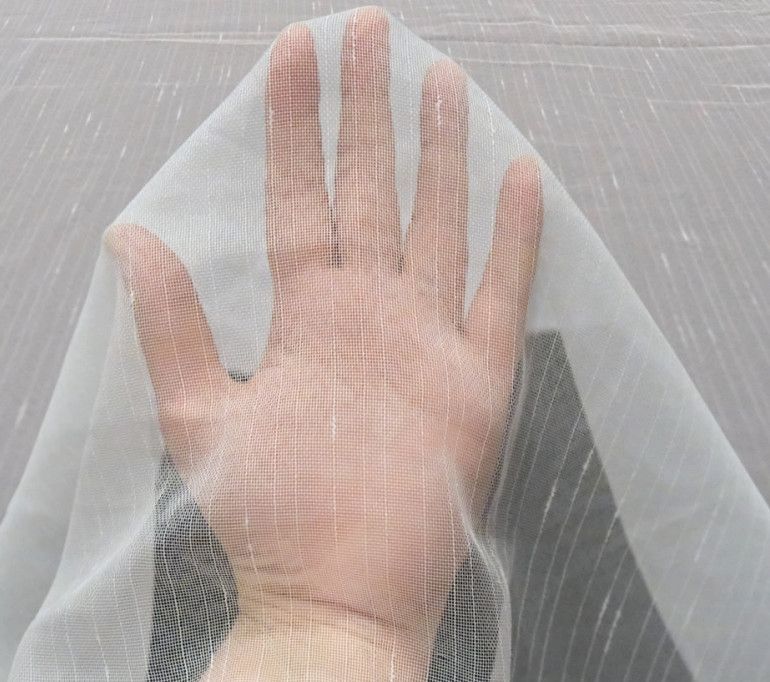 Hand pressing against a translucent plastic sheet over a gray surface.