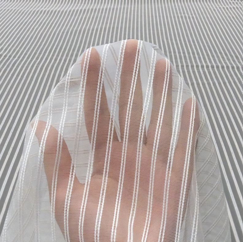Bare foot behind a sheer striped fabric curtain, with a gray patterned floor in the background