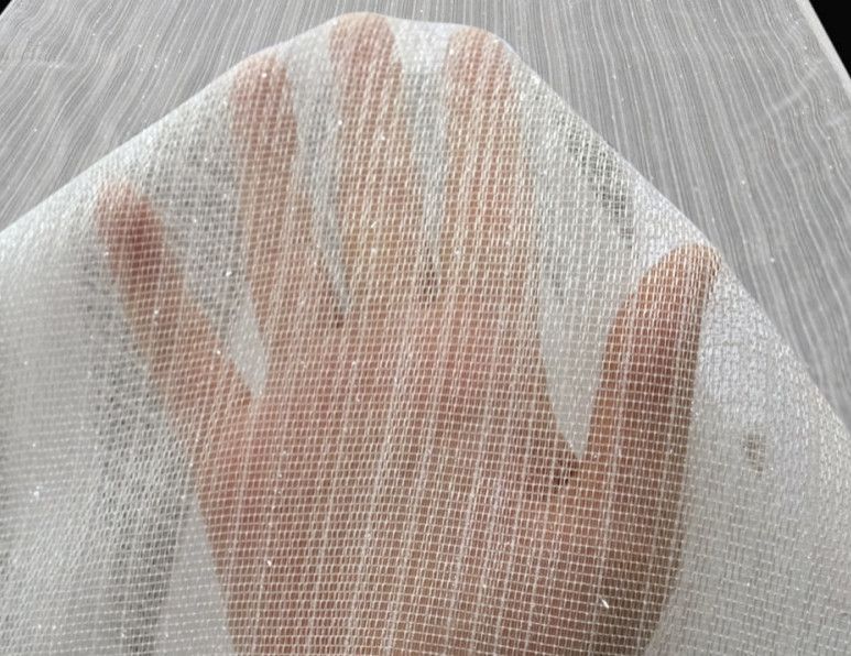 Hand pressing against sheer white fabric, creating a soft shadow silhouette