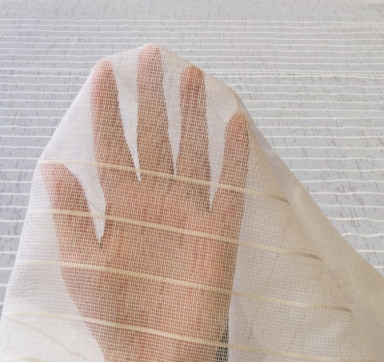 A hand seen through a sheer white mesh fabric against a light background.