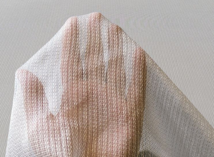 A hand wearing a translucent mesh glove against a light gray background.