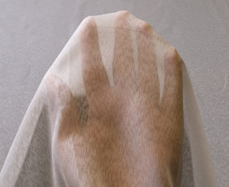 Sheer white fabric with a brown botanical pattern draped over a mannequin body