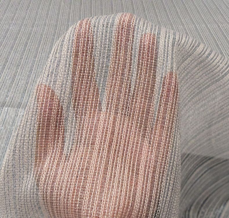 A hand pressing against a sheer mesh curtain, with soft light filtering through.
