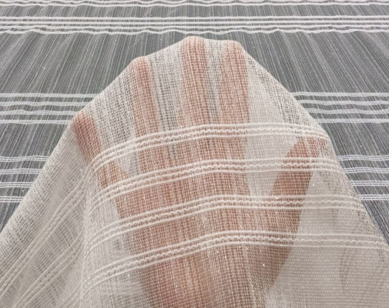 A foot under sheer white striped fabric on a gray striped background.
