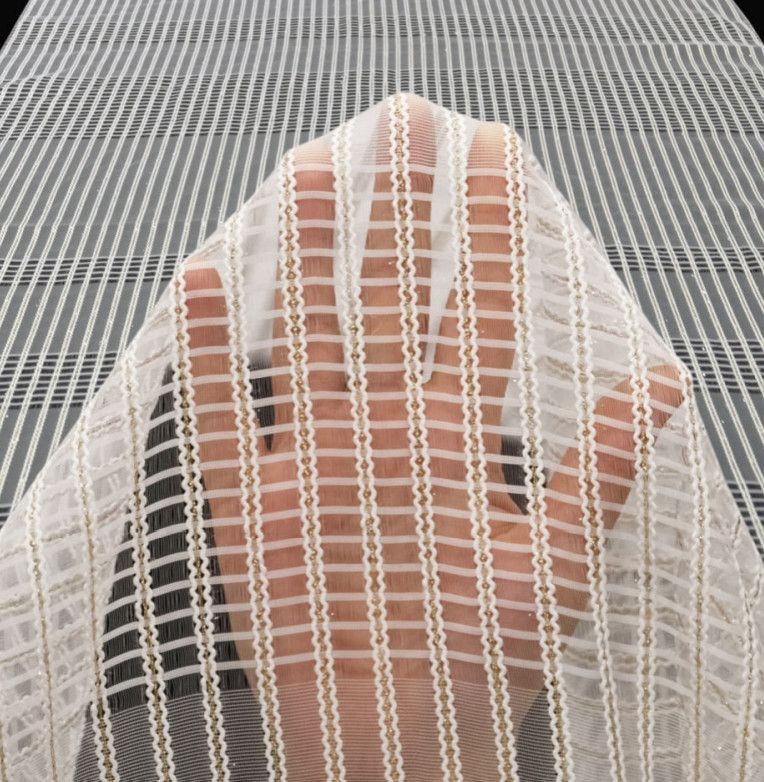Hand resting on a white mesh fabric over a gray striped surface