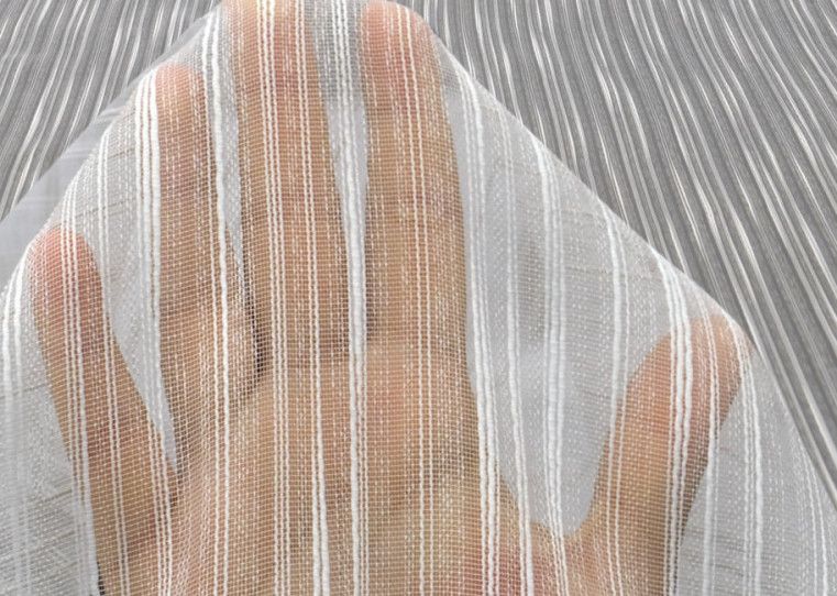 Person seen through a sheer white curtain with raised hands behind it