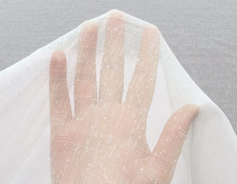 Hand pressing against sheer white fabric, visible in soft light