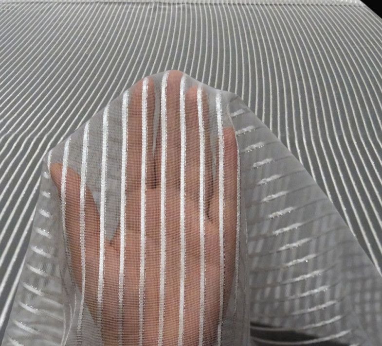Person peeking through a striped white veil on a textured gray background
