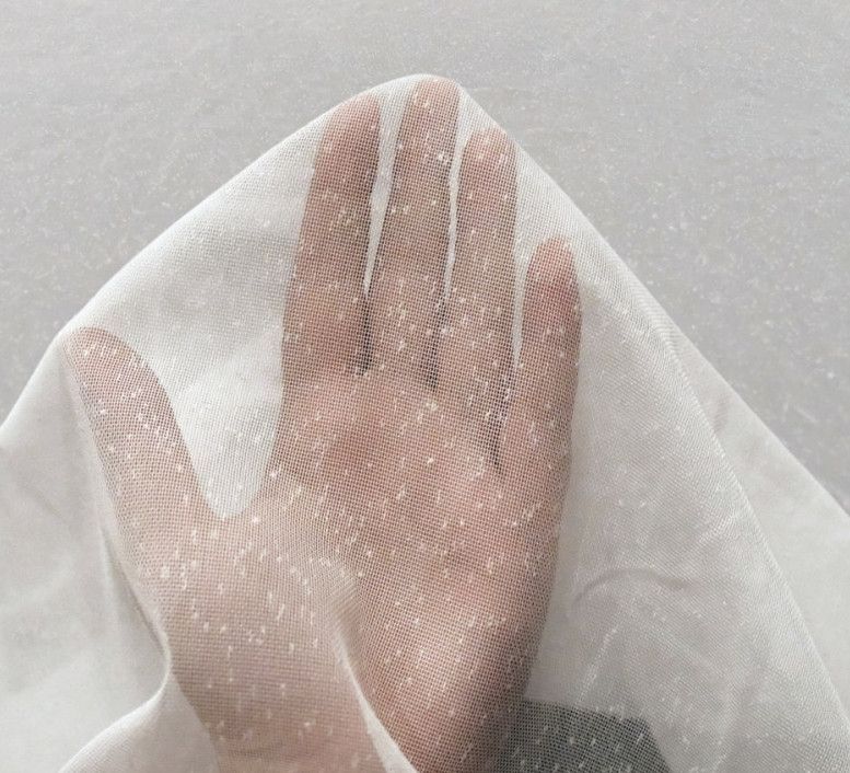Hand pressed against white mesh fabric against a light gray background