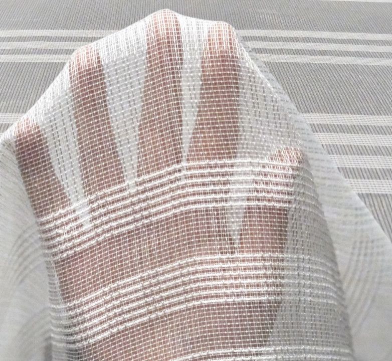 Close-up of a foot under a sheer striped fabric, with beige and white stripes