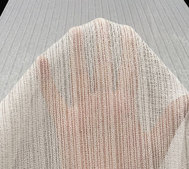 A hand presses against a translucent woven curtain, creating a soft blurred silhouette.
