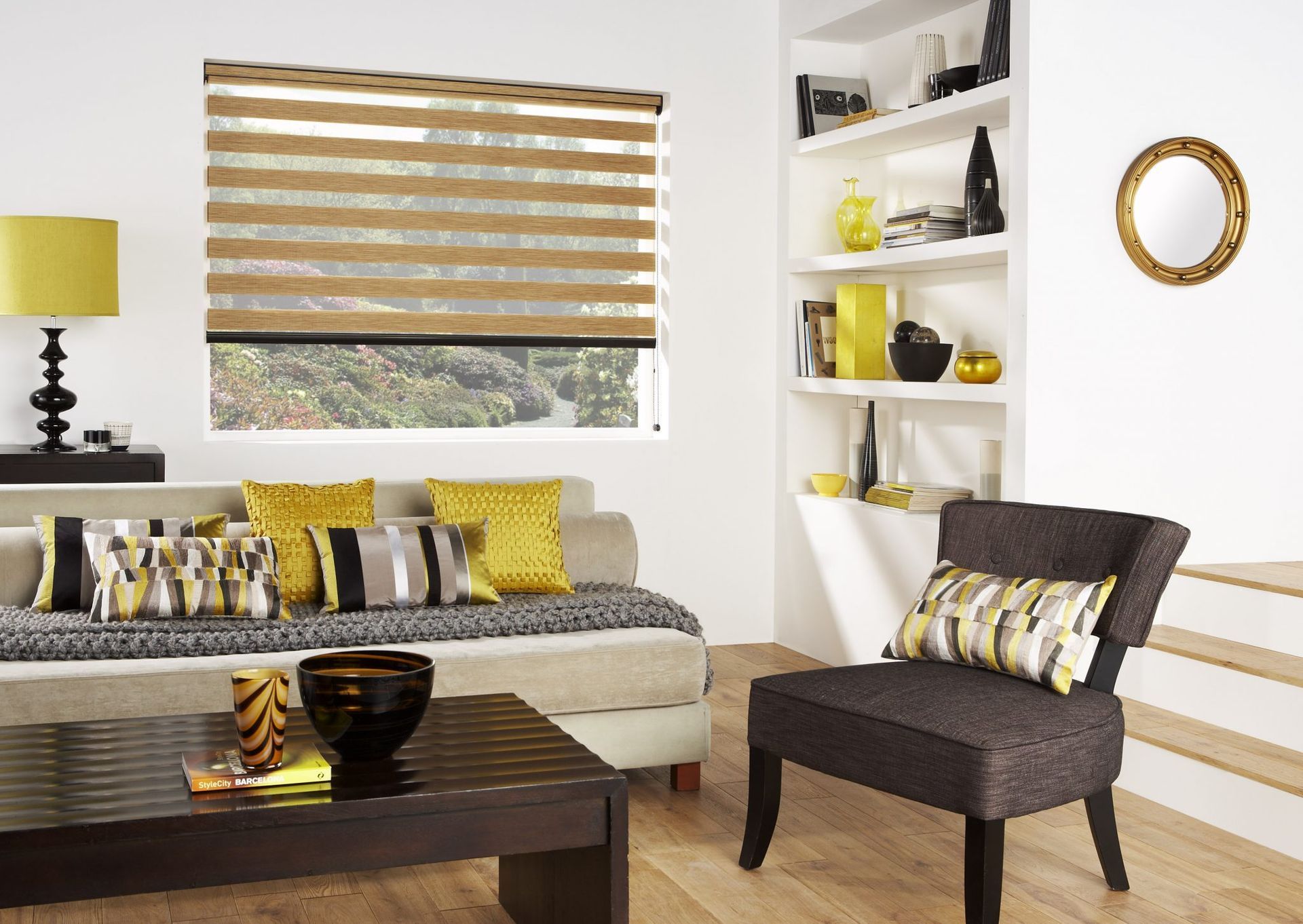 Modern living room with gray sofa, brown chair, striped blinds, yellow accents, and dark wood coffee table