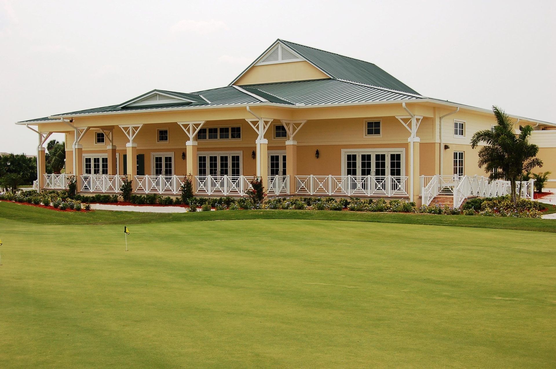Yellow and white building with green roof overlooking a green lawn.