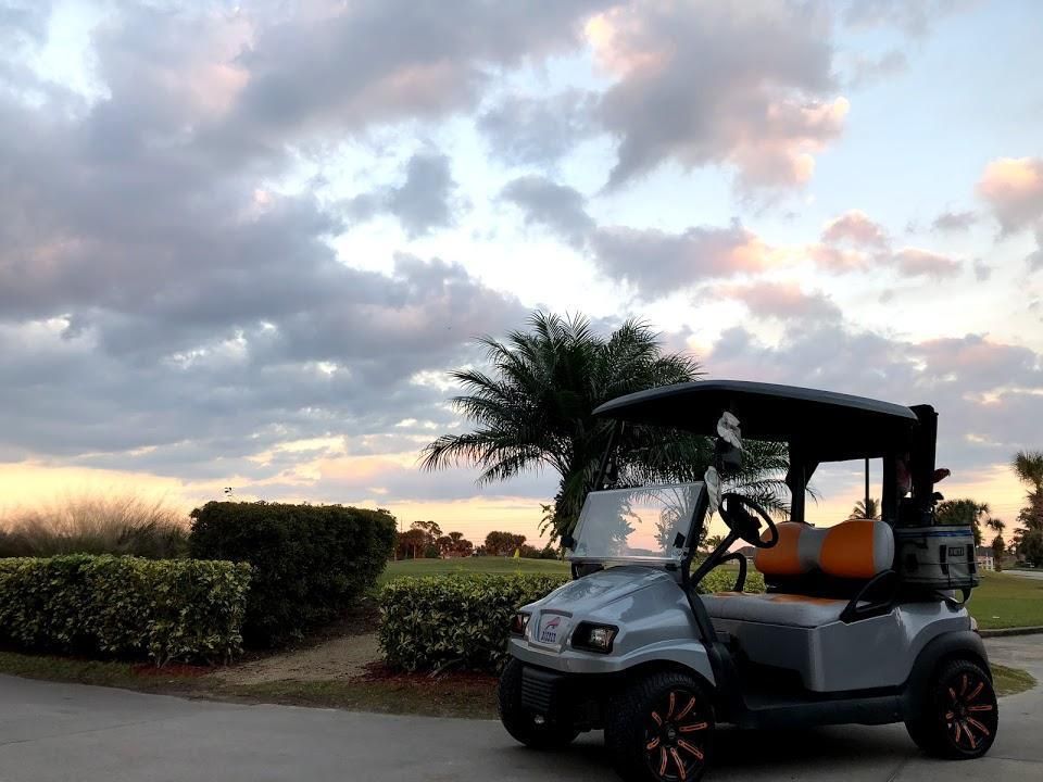 Golf cart parked on a path at dusk with a cloudy sky.
