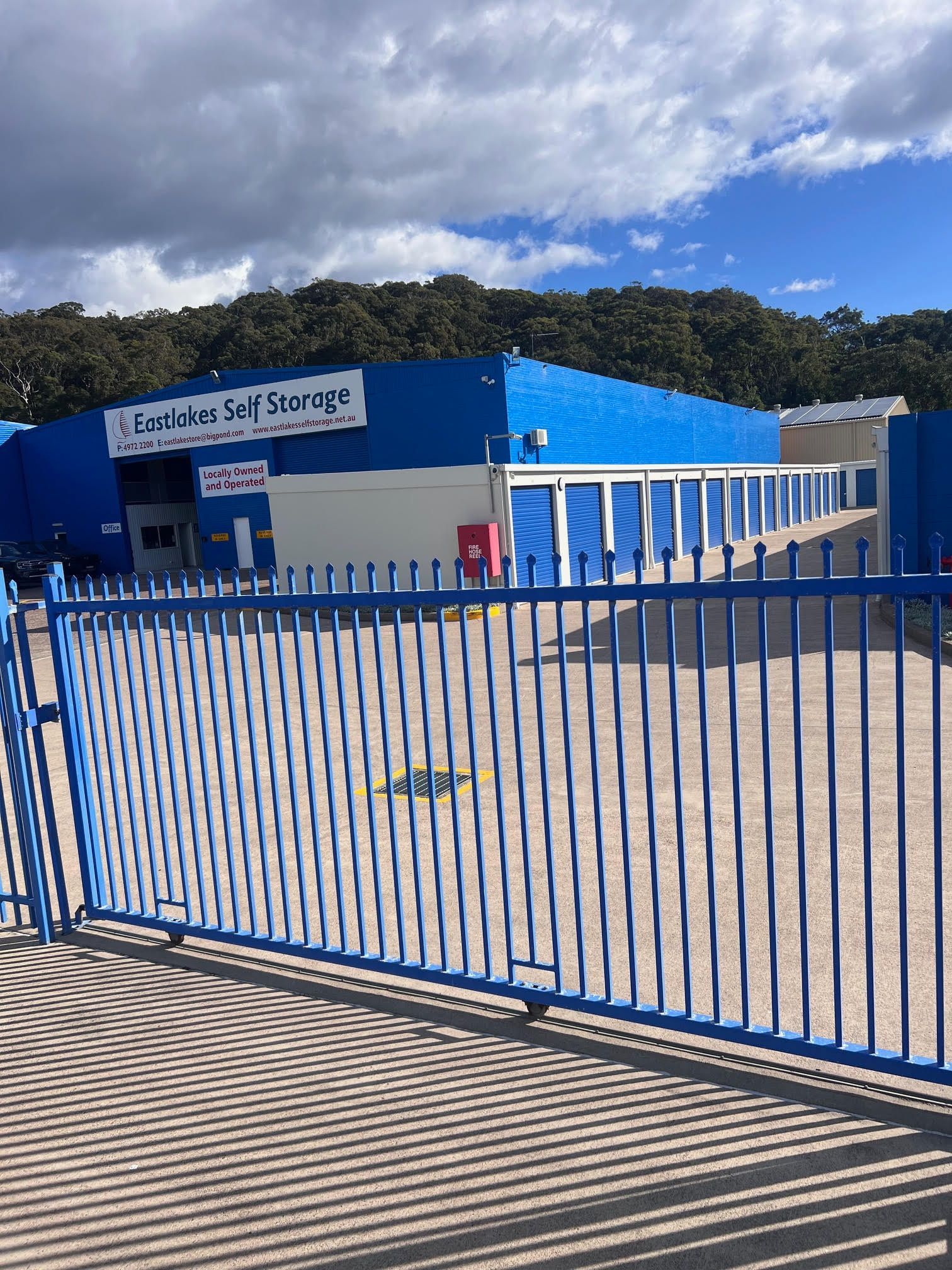 A blue fence is surrounding a large blue building.