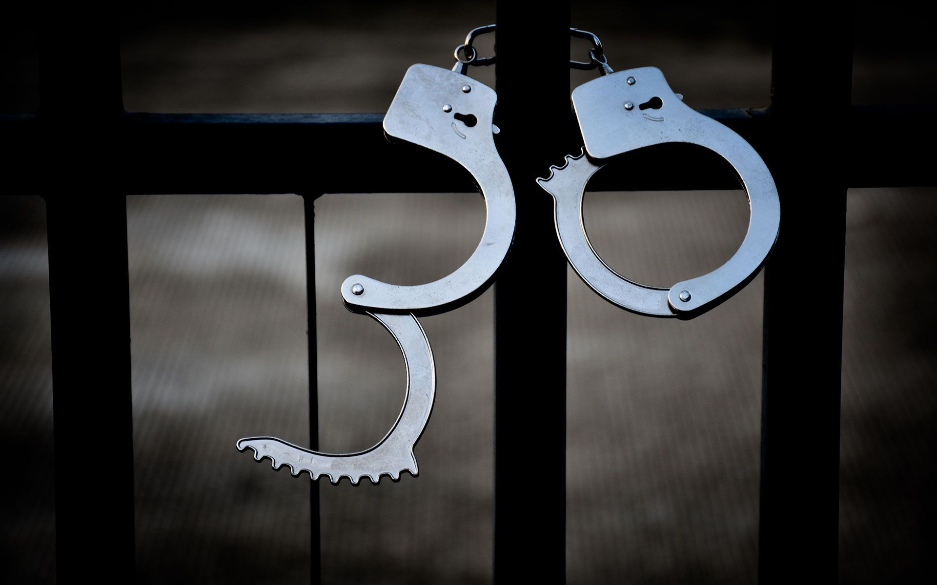 A pair of handcuffs are hanging on a fence