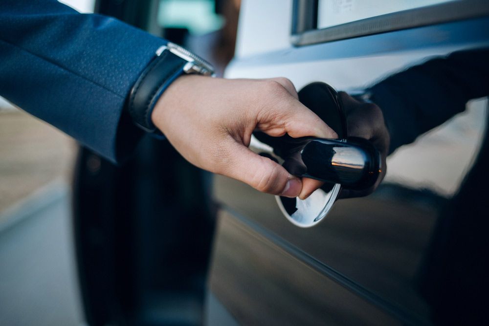 A Man in a Suit is Opening the Door of a Car — Dave's Used Cars In Stuart, NT