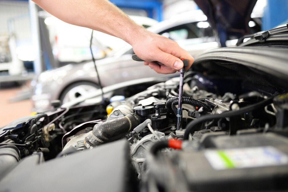 A Man is Working on the Engine of a Car With a Wrench — Dave's Used Cars In Stuart, NT