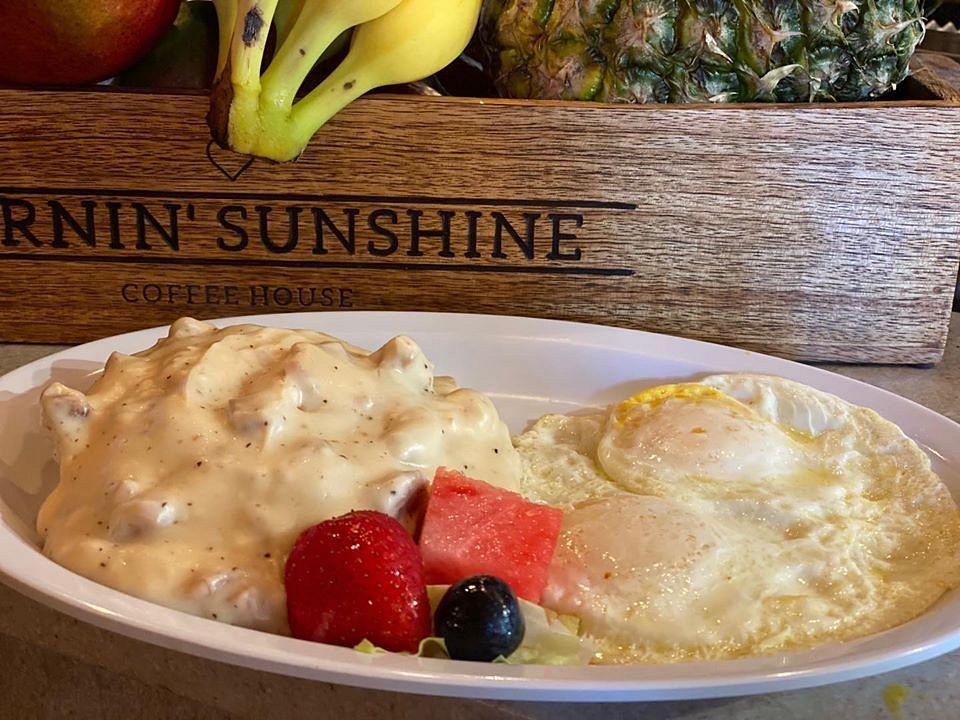 A plate of food with eggs , fruit and gravy on a table.