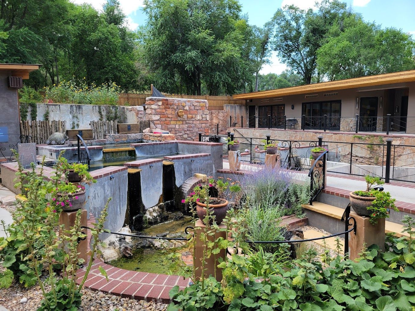 There is a pond in the middle of a garden in front of a house.