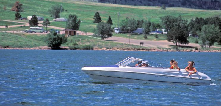Two people are riding a speed boat on a lake